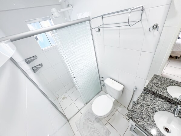 A modern bathroom with a glass shower enclosure, a white toilet, and a granite countertop sink.