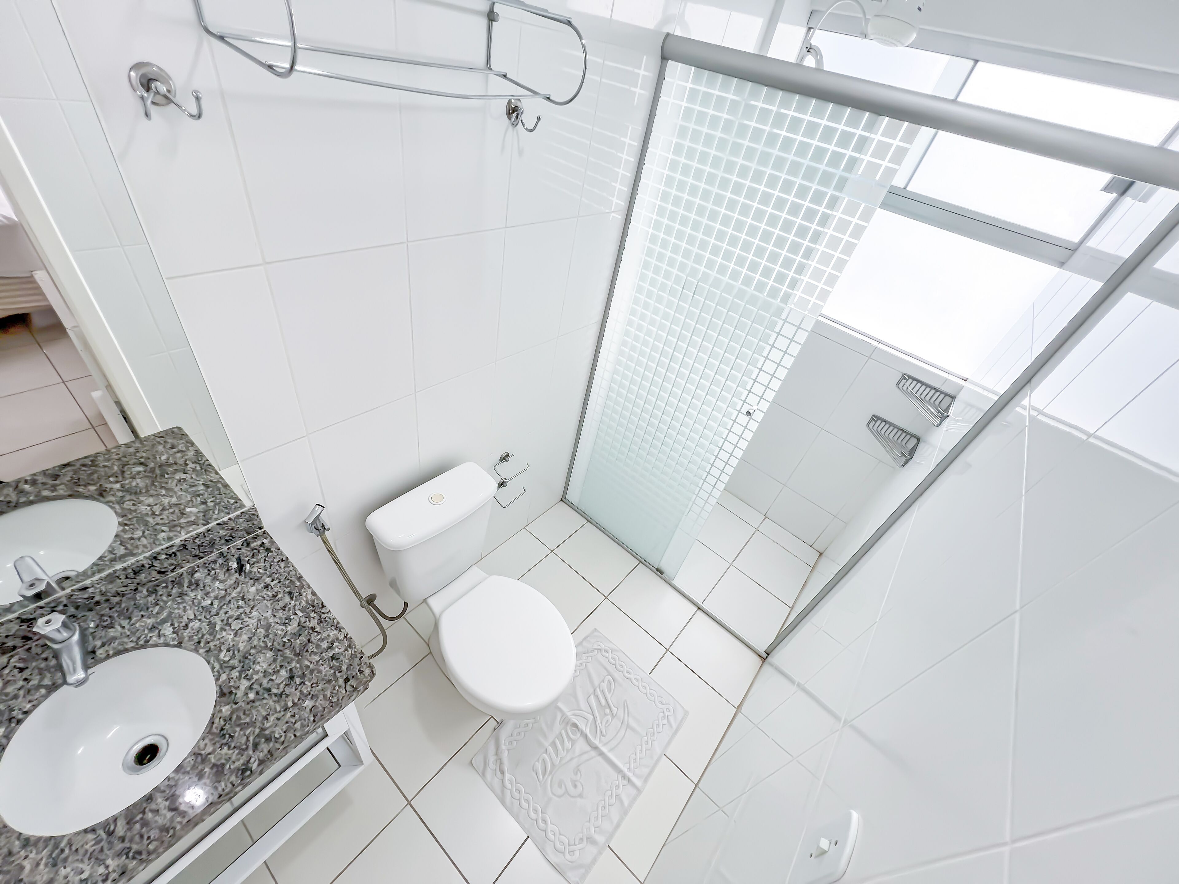 A modern bathroom with a double sink, toilet, and glass shower enclosure.