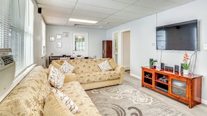 A living room with a sectional sofa, a flat-screen TV, and a wooden entertainment unit. - Cozy Keansburg Cottage: Walk to Beach & Boardwalk! (Keansburg)