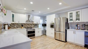 Una cocina moderna con armarios blancos, electrodomésticos de acero inoxidable y salpicadero de azulejos.