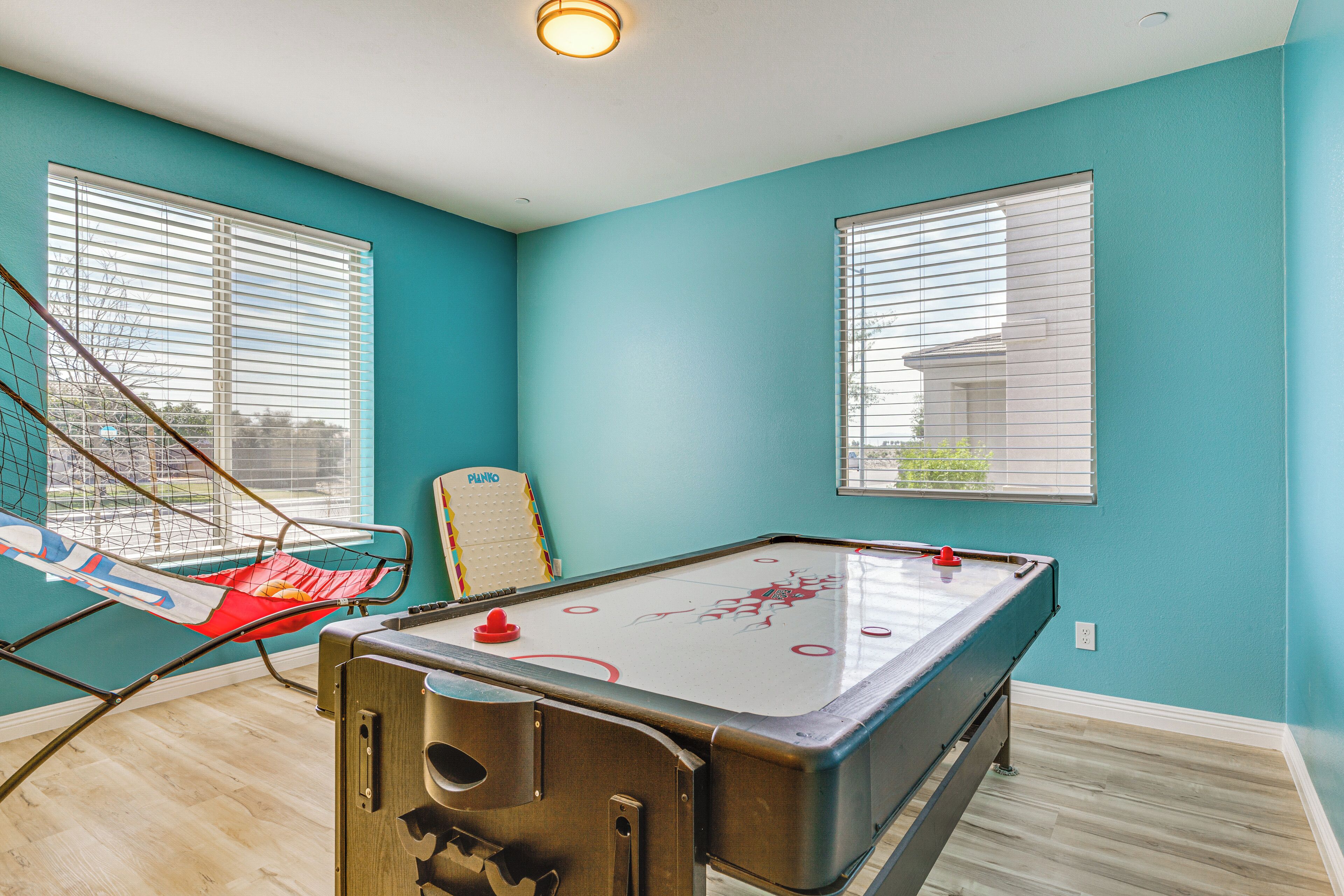A pool table in a room with teal walls and wooden flooring.
