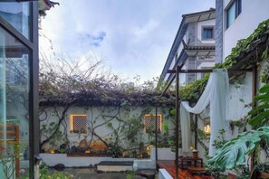 A courtyard with a traditional building, a small water feature, and a wooden bench. - Buxianshan Guesthouse (Dali City)