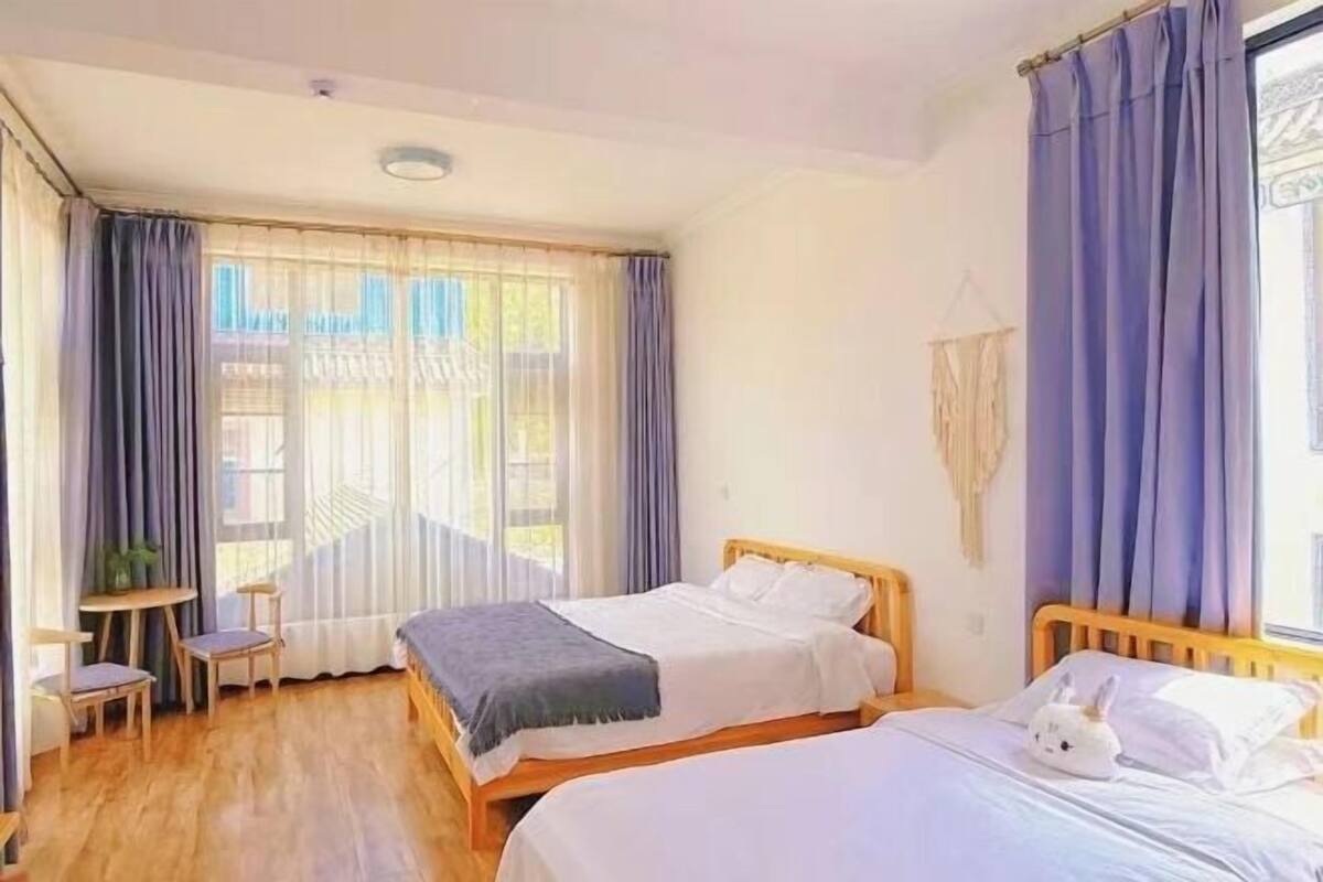 A bedroom with two beds, a small table, and a chair.