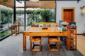 A wooden dining table with chairs, a vase with flowers, and a laptop on the table. - Buxianshan Guesthouse (Dali City)