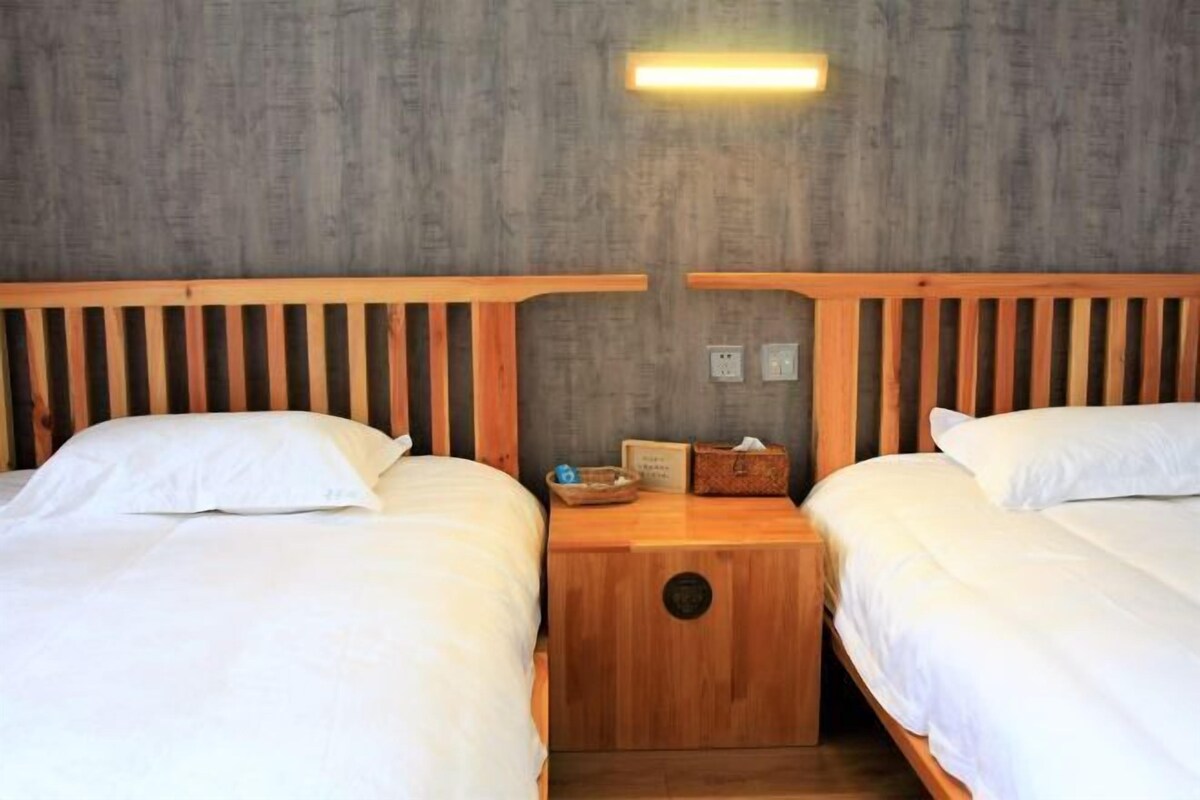 Ein Zimmer mit zwei Holzbetten, einem Nachttisch mit Lampe und einer Wandleuchte.