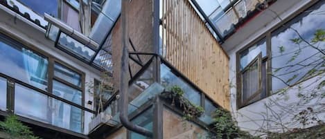 A multi-story building with a glass facade, wooden paneling, and a visible balcony.