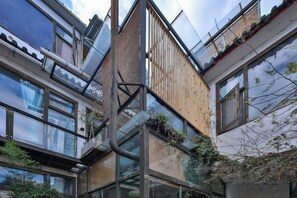 A multi-story building with a glass facade, wooden paneling, and a visible balcony. - Buxianshan Guesthouse (Dali City)