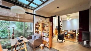 Amplia sala de estar con un ventanal grande, un sofá, una estantería de madera y una mesa de comedor.