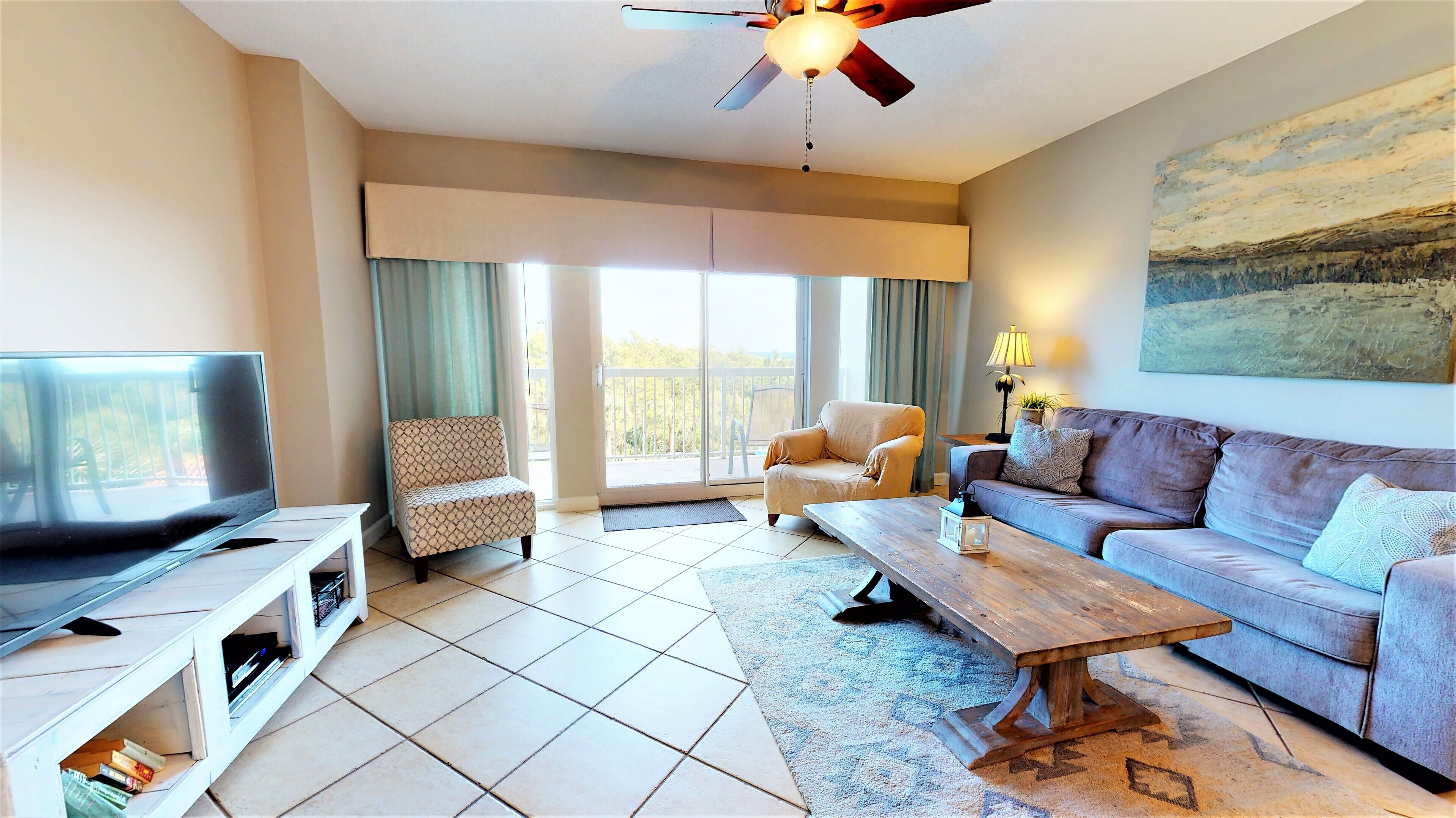 A living room with a television, sofa, armchair, and a ceiling fan.
