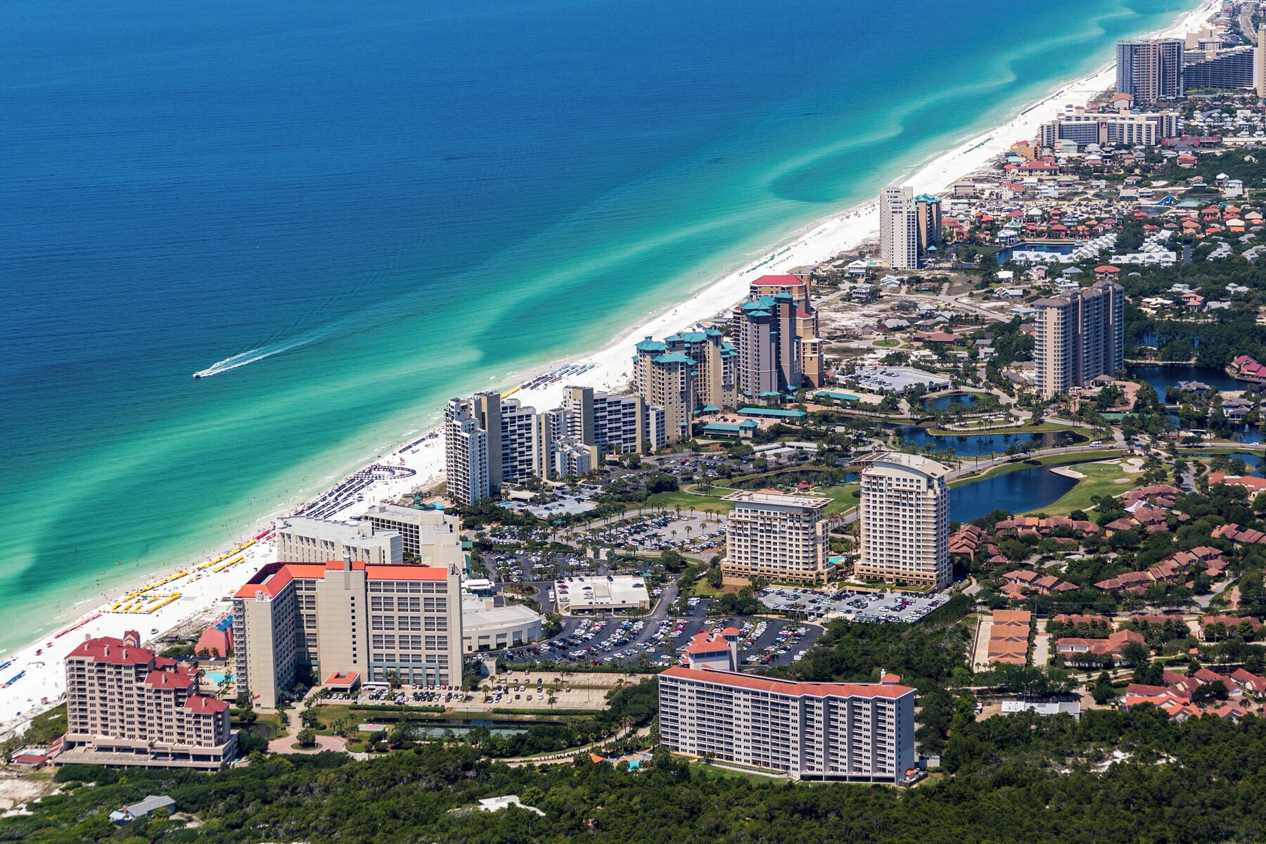 A coastal cityscape with high-rise hotels, a beach, and a marina.
