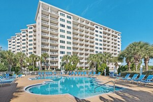 Un hotel con varias plantas, piscina y palmeras.