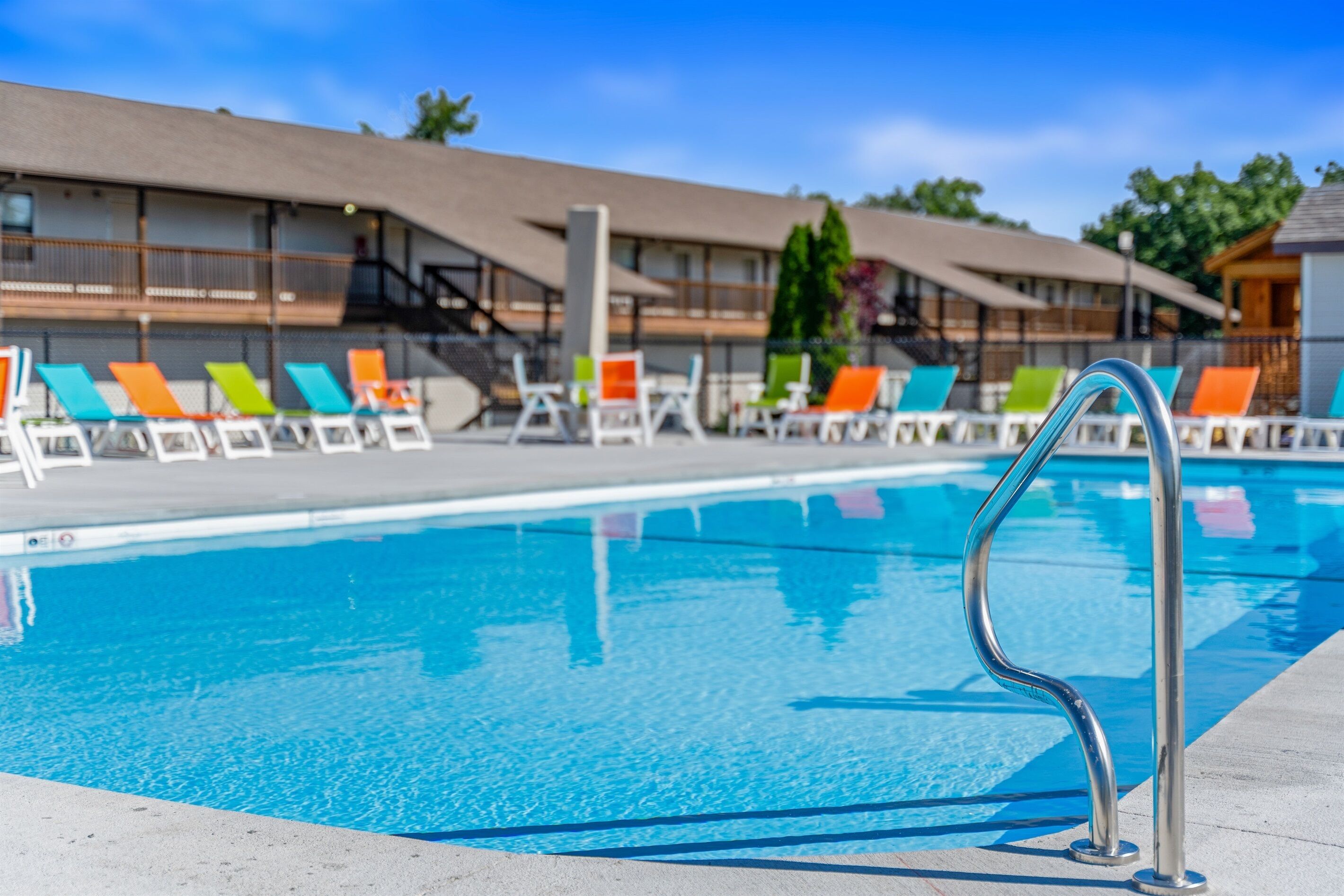 Una piscina con sillas de descanso y una escalera metálica.