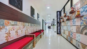 A hallway with benches and a tiled wall. - Hotel Ayaansh (Vadodara)
