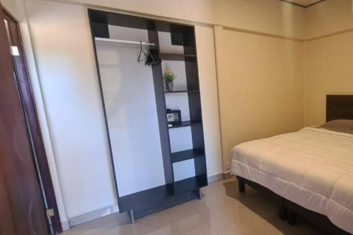 Une chambre à coucher avec un lit, une armoire et une petite étagère sur laquelle sont posés quelques objets.