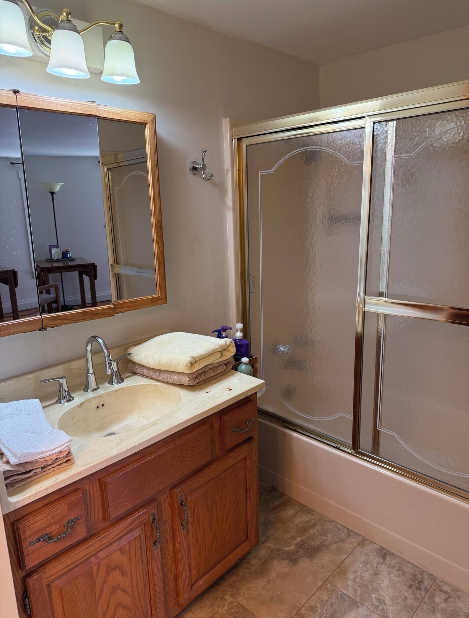 A bathroom with a vanity, sink, mirror, and a glass shower enclosure.