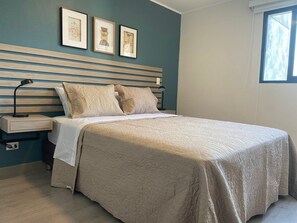 A bedroom with a bed, two nightstands, a window, and three framed artworks on the wall. - Redibuk - Premiere 1BR in San Isidro (Lima)