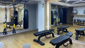 A gym with exercise equipment, benches, and a punching bag. - Redibuk - Premiere 1BR in San Isidro (Lima)