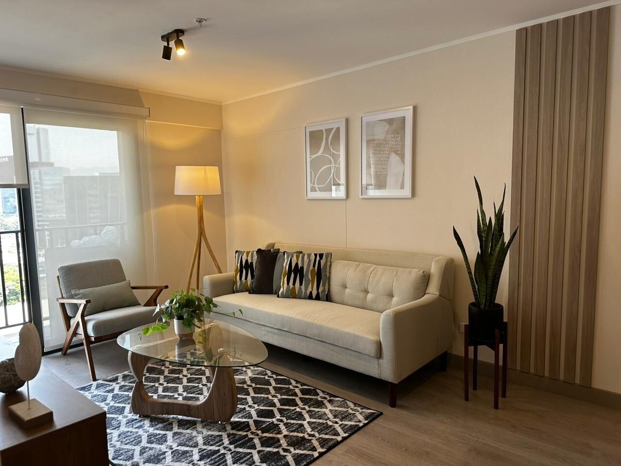 A modern living room with a sofa, armchair, coffee table, and a potted plant.