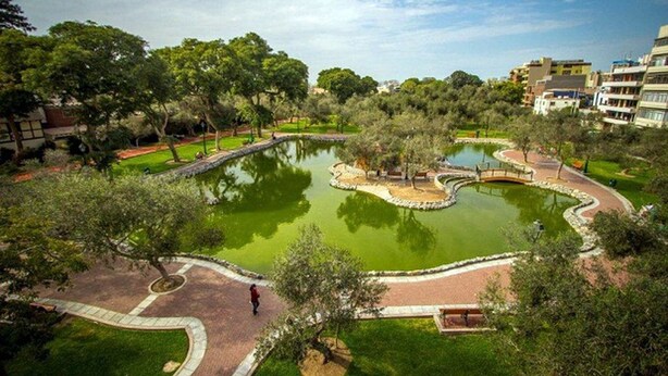 A park with a pond, pathways, and surrounding greenery. - Redibuk - Premiere 1BR in San Isidro (Lima)