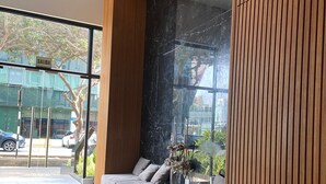 A modern interior with a large window, a wooden panel wall, and a seating area with cushions. - Redibuk - Premiere 1BR in San Isidro (Lima)