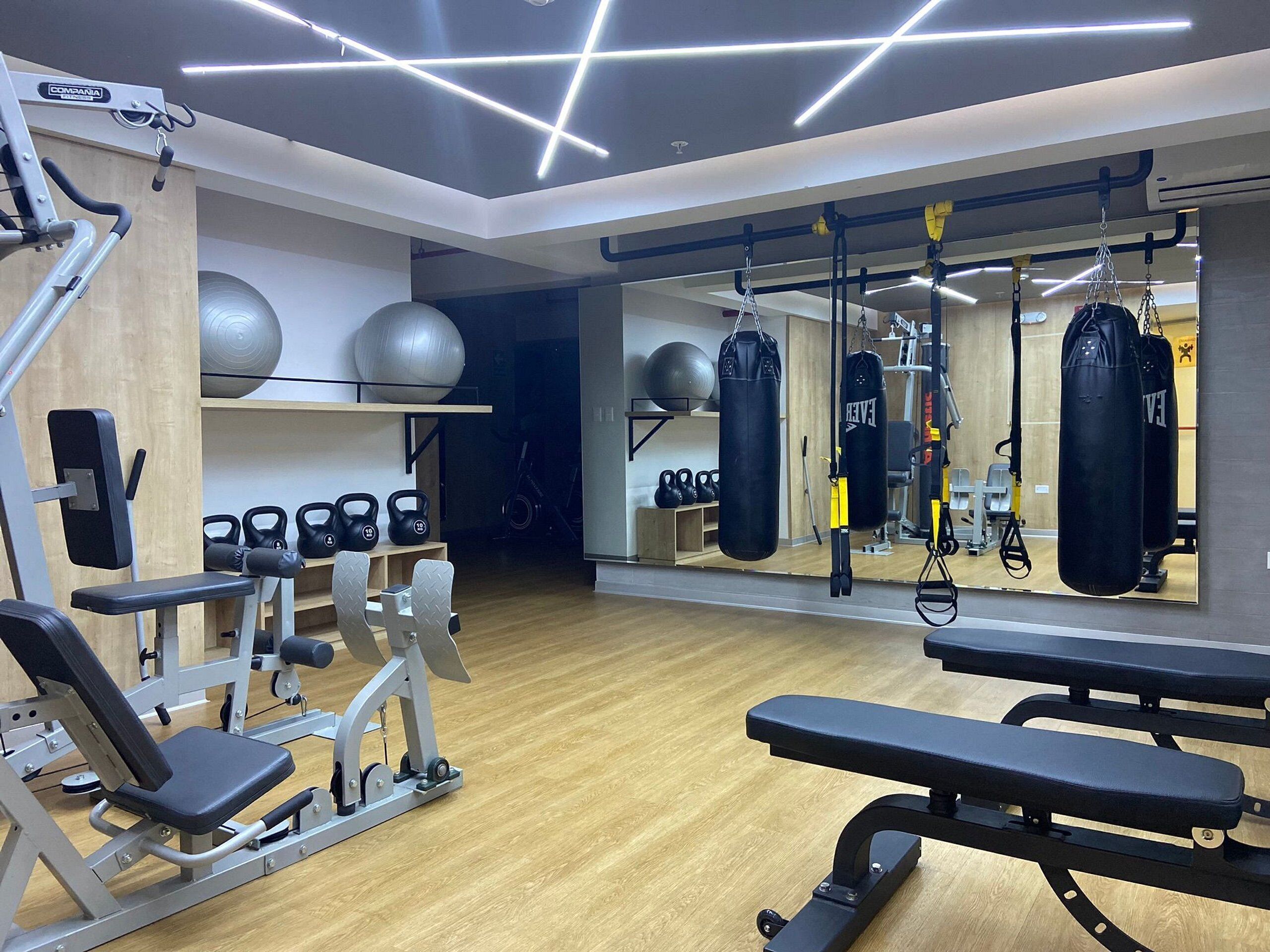 A gym with exercise equipment, benches, and a mirrored wall.