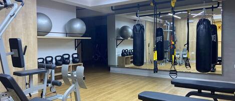 A gym with exercise equipment, benches, and a mirrored wall.