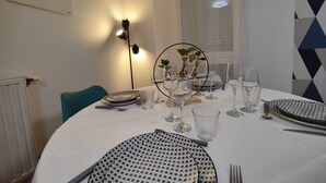 A dining area with a round table set for four, featuring patterned plates and clear glassware. - Quietstay 20' Paris, Connected Home Avec Terrasse (Massy)