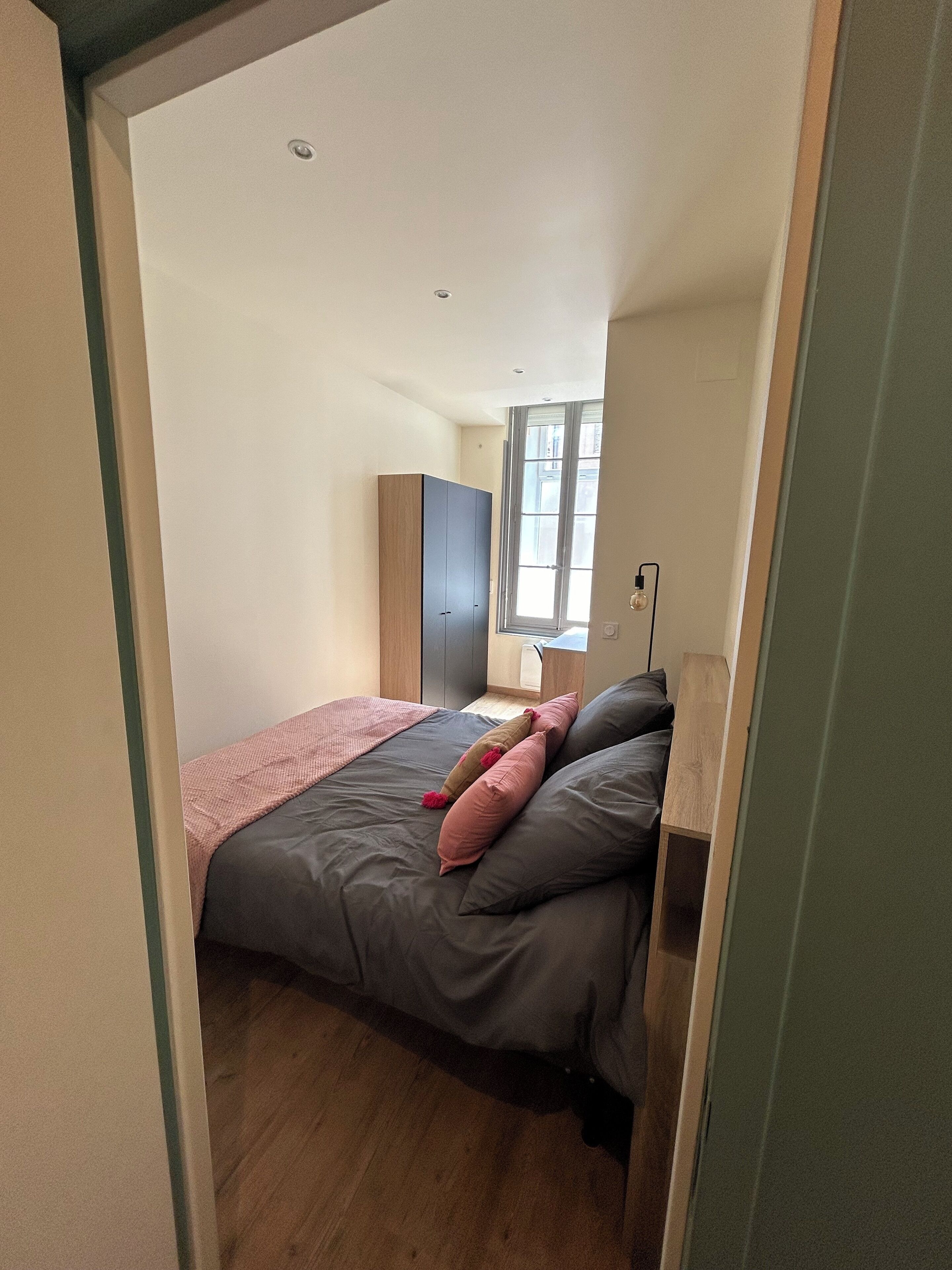 Une chambre à coucher avec un lit, une armoire et une fenêtre.