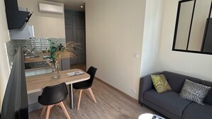 A modern living room with a sofa, coffee table, and dining area. - Appartement Centre Ville (Castelnaudary)