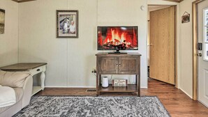 Ein gemütliches Wohnzimmer mit Kamin, einem Fernseher auf einem Holzboden und einem Bild im Bilderrahmen an der Wand, sowie einem Teppich auf dem Boden.