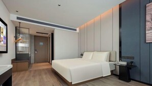 A modern hotel room with a bed, bedside table, and a wall-mounted artwork. - Mohan Huating Hotel (Mengla)