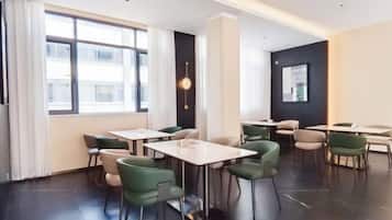 Un comedor moderno con mesas, sillas, ventanas amplias y una pared de acento negra.