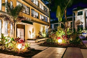 A hotel with a multi-story structure, outdoor lighting, and landscaped gardens.