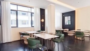 A modern dining area with tables and chairs, large windows, and a black accent wall. - Mohan Huating Hotel (Mengla)