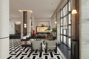A modern interior with a geometric patterned floor, a seating area with white chairs, and a staircase leading to another level.