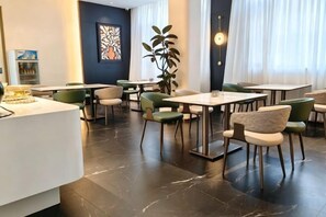 A modern hotel lobby with a reception desk, seating area, and large windows.