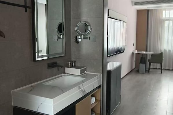 Un bany modern amb un mirall gran, un lavabo i una televisió.