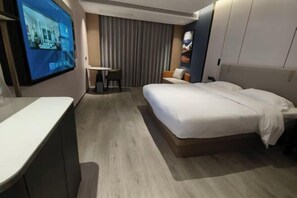 Habitació d'hotel moderna amb un llit gran, escriptori, cadira i televisió penjada a la paret.