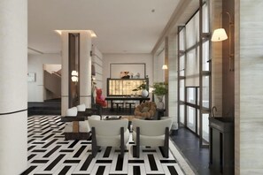 A hotel lobby with a patterned floor, seating area, and a reception desk.