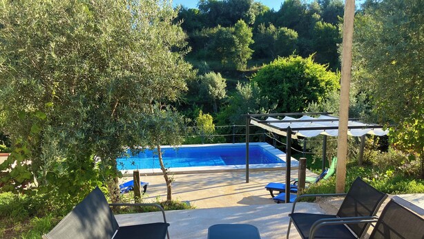 An outdoor pool area with a pergola, lounge chairs, and a clear view of the pool. - Relax, swim and unwind at this Portuguese house 5 minutes from Sertã, Portugal. (Sertã)
