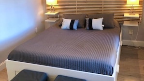 Une chambre à coucher avec un grand lit, deux tables de chevet avec des lampes et une tête de lit en bois.