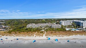 A beachfront hotel with multiple buildings, a sandy beach, and umbrellas.