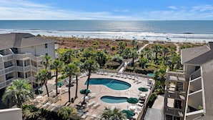 A resort with a pool area, palm trees, and a view of the beach.