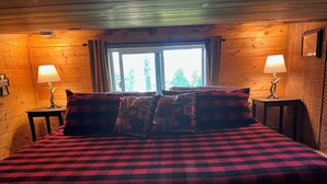 Une chambre confortable dans un chalet, avec un grand lit, deux tables de chevet avec des lampes et une fenêtre avec des rideaux.