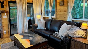 L’intérieur d’un chalet accueillant, avec un canapé en cuir, une table basse en bois et une cheminée.