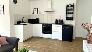 Una cocina moderna con armarios blancos, un refrigerador negro y un horno empotrado.