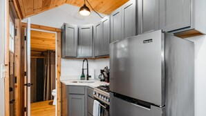 Eine moderne Küche mit grauen Schränken, einem Edelstahlkühlschrank und einer Holzbalkendecke.