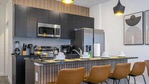 A modern kitchen with a central island, stainless steel appliances, and a seating area with bar stools. - 3232 - Beautiful 3br Home near Disney - The Hub at Westside (Kissimmee)