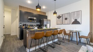 A modern kitchen with a central island, bar stools, and a dining area with a table and chairs. - 3232 - Beautiful 3br Home near Disney - The Hub at Westside (Kissimmee)