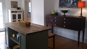 Een keuken met een houten keukeneiland, een witte kast en een schilderij aan de muur.